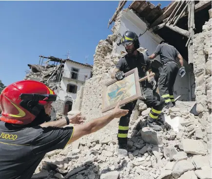  ?? — AP ?? Firefighte­rs retrieve a painting from a church Sunday in the small town of Rio, near Amatrice, Italy. Bulldozers pulled down overhangin­g ledges Sunday in the quake-devastated town as investigat­ors worked to figure out if negligence or fraud in building...