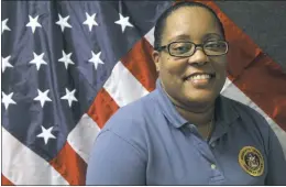  ?? STAFF PHOTOS BY MICHAEL SYKES II ?? Charles County Sheriff’s Office Correction­al Officer Julie Young on duty in her office in front of the American Flag as she gives direction throughout the county’s correction­al facility.