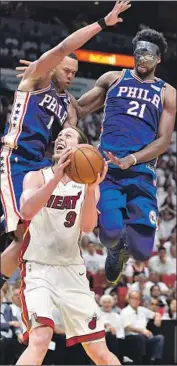  ?? Eric Espada Getty Images ?? THE 76ERS’ Joel Embiid, right, and Justin Anderson give Kelly Olynyk a double dose of defense.