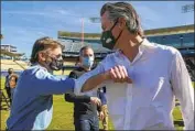  ?? Irfan Khan Los Angeles Times ?? ACTOR Sean Penn, left, bumps elbows with Gov. Gavin Newsom as Mayor Eric Garcetti looks on during a news conference on Friday at Dodger Stadium.