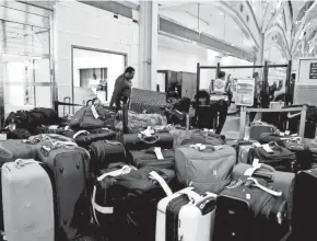  ?? GETTY IMAGES ?? TSA agents sort through luggage in the departure terminal at the Ronald Reagan Washington National Airport on Monday in Arlington, Va. According to media reports, at least 2,600 more flights were canceled Monday.