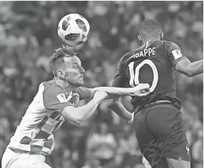  ??  ?? France forward Kylian Mbappe, right, vies for a header with Croatia midfielder Ivan Rakitic on Sunday. JEWEL SAMAD/AFP/GETTY IMAGES