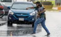  ?? Photo by Leslie Pableo ?? A pedestrian takes chances to cross the road with his child during showers in Discovery Gardens. —