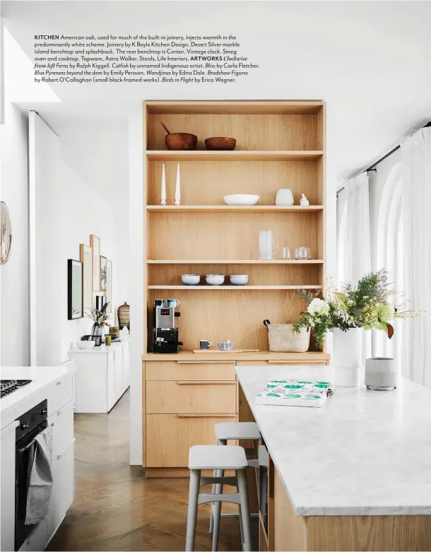  ??  ?? KITCHEN American oak, used for much of the built-in joinery, injects warmth in the predominan­tly white scheme. Joinery by K Boyle Kitchen Design. Desert Silver marble island benchtop and splashback. The rear benchtop is Corian. Vintage clock. Smeg oven and cooktop. Tapware, Astra Walker. Stools, Life Interiors. ARTWORKS Clockwise from left Ferns by Ralph Kiggell. Catfish by unnamed Indigenous artist. Bliss by Carla Fletcher. Blue Pyrenees beyond the dam by Emily Persson. Wandjinas by Edna Dale. Bradshaw Figures by Robert O’Callaghan (small black-framed works). Birds in Flight by Erica Wagner.