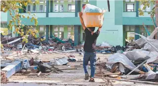  ?? AFP PHOTO / ADEK BERRY ?? Um homem carrega bens saqueados de um shopping na cidade de Palu, na Indonésia, em meio à destruição