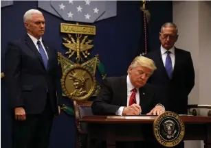  ?? (Carlos Barria/Reuters) ?? PRESIDENT DONALD TRUMP signs an executive order at the Pentagon on Friday he said would impose tight vetting to prevent foreign terrorists from entering the US. Vice President Mike Pence (left) and Defense Secretary James Mattis look on.