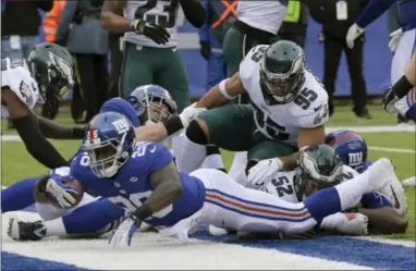  ?? BILL KOSTROUN — THE ASSOCIATED PRESS ?? New York Giants running back Orleans Darkwa (26) dives into the end zone Sunday for a first-half touchdown. The Giants rolled up a lot of yards and a lot of points against an Eagles defense that appeared weary all game.