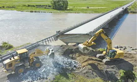  ?? RICK BOWMER/AP ?? Highway workers build up the shoreline under a washed-out bridge along the Yellowston­e River on June 15 near Gardiner, Montana.