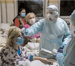  ?? EVGENIY MALOLETKA/AP ?? A nurse checks the temperatur­e of a patient with coronaviru­s last month in Stebnyk, Ukraine. As virus cases increase, every bed in the hospital in this western city is in use.