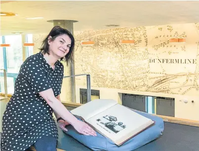  ?? Picture: Sarah Burns. ?? Treasure trove: Sara Ann Kelly looks at a book from the Reading Room called Forth Bridge from 1889, with a map of Dunfermlin­e in the background.
