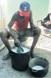  ??  ?? Lewie Foster removing the first-stage formation of castor oil into another pot.