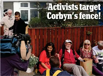  ??  ?? Sitdown protest: The campaigner­s glue themselves to Mr Corbyn’s fence