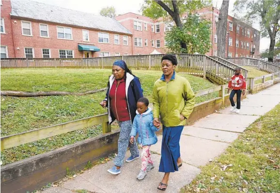  ?? KIM HAIRSTON/BALTIMORE SUN ?? Translator Juliah Kangara, from left, walks with Anifa Sanza and her daughter Bahati, 5, as her son Moses, 10, follows. Anifa lives with her two children in Ashburton.