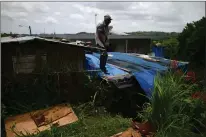  ??  ?? Wilfredo Negron secures the metal roofing on one of his properties July 13 in preparatio­n for the hurricane season in Corozal, Puerto Rico. Nearly three years after Hurricane Maria tore through Puerto Rico, tens of thousands of homes remain badly damaged, many people face a new hurricane season under fading blue tarp roofs and the latest program to solve the housing crisis hasn’t yet finished a single home. (AP Photo/Carlos Giusti)