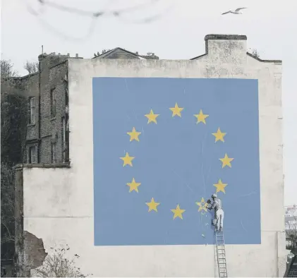  ??  ?? 0 A mural by Banksy in Dover shows a worker chipping away at one of the stars on a European Union flag