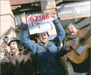  ?? MARCELO DEL POZO / REUTERS ?? People celebrate as a man holds up a first prize notice of Spain’s Christmas Lottery “El Gordo” (The Fat One) outside the lottery shop where the ticket was sold in Sanlucar la Mayor, southern Spain, on Sunday.