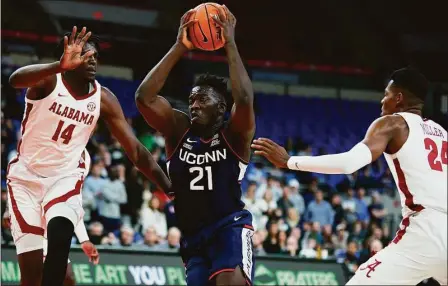 ?? Craig Mitchelldy­er / Associated Press ?? UConn’s Adama Sanogo, center, drives to the basket between Alabama’s Charles Bediako, left, and Brandon Miller during the first half on Friday.