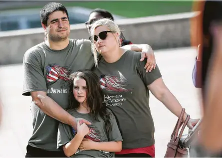  ?? Elizabeth Conley / Houston Chronicle ?? Army veteran Justine Phillips listens to speakers with Hand and Rylie Henderson on Saturday at City Hall. The veterans marched to celebrate progress and speak out against abuse and challenges they face in a male-dominated sphere.