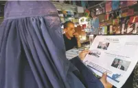  ?? RAHMAT GUL/THE ASSOCIATED PRESS ?? An Afghan woman reads a local newspaper Tuesday in Kabul, Afghanista­n. Reversing his past calls for a speedy exit, President Donald Trump recommitte­d the United States to the 16-year-old war in Afghanista­n on Monday night, declaring U.S. troops must...