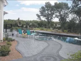  ??  ?? A flowing Stampcrete patio surrounds the pool area and built-in hot tub at the custom home on Brainerd Road in Niantic. The residence overlooks a saltwater marsh.