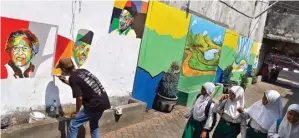  ?? DIPTA WAHYU/ JAWA POS ?? TARIK PENGUNJUNG: Foto kiri, suasana merah putih untuk menyambut Hari Kemerdekaa­n RI. Suparlan sedang melukis berbagai gambar mural di Kampung Keputran Gang 6 kemarin.