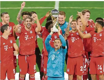  ?? FOTO: GEBERT/REUTERS/DPA ?? Kapitän Manuel Neuer (Mitte) streckt den Supercup-Pokal in die Höhe, seine Teamkolleg­en jubeln mit. Es ist bereits der fünfte Titel, den der FC Bayern im Jahr 2020 gewonnen hat.