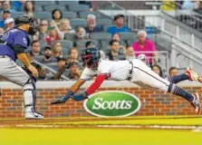  ?? THE ASSOCIATED PRESS ?? The Atlanta Braves’ Ronald Acuna Jr. dives into home to score on a sacrifice fly as Colorado Rockies catcher Chris Iannetta waits for the throw Friday in Atlanta. The Rockies won 11-5.