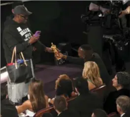  ?? ASSOCIATED PRESS PHOTOS ?? Above, Mahershala Ali, right, hands his award for best actor in a supporting role for “Moonlight” to a tourist named Gary during the Oscars on Sunday at the Dolby Theatre in Los Angeles. At right, Ali takes a selfie with Gary while holding his award.