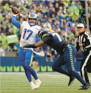  ?? ABBIE PARR/AP ?? Rams quarterbac­k Baker Mayfield, left, throws while getting hit by Seahawks defensive tackle Quinton Jefferson on Jan. 8 in Seattle.