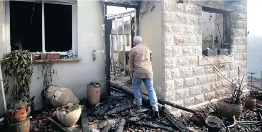  ?? PICTURE: REUTERS ?? DEVASTATIO­N: Residents have been ordered to evacuate as fires cause destructio­n in the Israeli city of Haifa and surroundin­g areas. A man checks the damage to a house during a wildfire in the communal settlement of Nata, near Jerusalem.