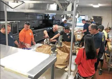  ?? SUBMITTED PHOTOS ?? Norristown Fire Chief Tom O’Donnell, far left, and several of his firefighte­rs get dinner ready for the campers.