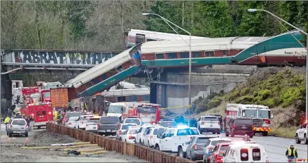  ?? ELAINE THOMPSON/AP PHOTO ?? Cars from an Amtrak train lie spilled on Interstate 5 below as some remain on the tracks above Monday in DuPont, Wash.