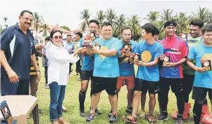  ??  ?? TAHNIAH: Mary menyampaik­an piala kepada ketua pasukan Good Wood dari Miri yang menjuarai kejohanan hoki di Miri semalam.