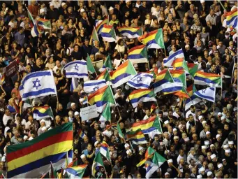  ?? (Reuters) ?? DRUZE TOGETHER with others wave both Druze and Israeli flags, taking part in a rally to protest the Jewish Nation-State Law in Tel Aviv’s Rabin Square on August 4.