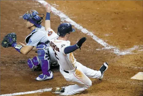  ?? Bob Levey/Getty Images ?? Houston's Alex Bregman slides safely in to home on a double by Jose Altuve in the seventh inning, putting the Astros ahead of the Dodgers in Game 5 of the World Series Sunday night. Bregman hit the game-winning single in the bottom of the 10th.