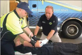 ?? Kaitlyn Rigdon/News-Times ?? Packing: Left, Trey Johnson, ProMed paramedic and Ken Kelley, ProMed CEO, demonstrat­es “wound packing” on a training dummy during a Stop the Bleed training session.