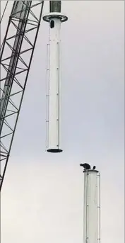  ?? Irfan Khan Los Angeles Times ?? ERIC MADRIGAL, left, and Dan Cobb wait for a crane to deliver the last piece of the spire. Its top 18 feet will glow with LED lights: red, blue, green or gold.