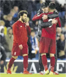  ?? (Photo: AFP) ?? Liverpool’s German Manager Jurgen Klopp (centre) embraces Liverpool’s Brazilian midfielder Roberto Firmino on the pitch after the English Premier League match against Brighton and Hove Albion at the American Express Community Stadium in Brighton, southern England, yesterday.