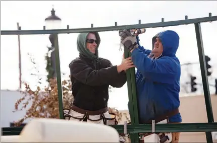  ?? EILISH PALMER/RIVER VALLEY & OZARK EDITION ?? Lumas Barker, left, and Joe Stoute brave the cold last week to begin assembling the 54-foot artificial Christmas tree at Rogers Plaza in downtown Conway. The tree was purchased last year for $134,000 from Get Lit LLC of Springdale, which went out of...