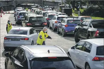  ?? Mark Baker Associated Press ?? VEHICLES LINE UP at a coronaviru­s testing clinic Saturday in Sydney, Australia. Health experts say one reason for the current surge in cases has been politician­s’ reluctance to break their promises of relaxing rules.