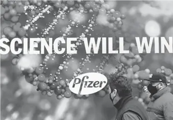  ?? ANGELAWEIS­S/GETTY-AFP ?? People walk past Pfizer headquarte­rs in New York. The COVID-19 vaccine developed by Pfizer and BioNTech passed a crucial milestone Thursday for use in a widespread inoculatio­n campaign in the United States.