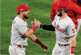  ?? Harry How/Getty Images ?? Sluggers Kyle Schwarber, left, and Bryce Harper each hit solo homers Tuesday to provide the Phillies with just enough offense to top the Padres in Game 1.