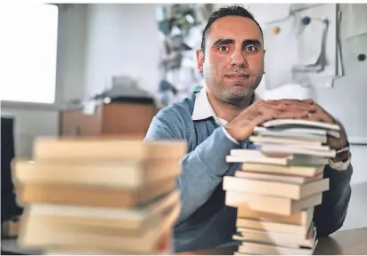  ?? RP-FOTO: STEPHAN KÖHLEN ?? Pädagoge Özkan Aksoy mit einem Stapel Bücher in seinem Büro im Erkrather Jugendamt.