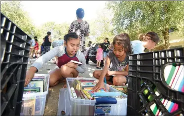  ?? NWA Democrat-Gazette/FLIP PUTTHOFF ?? Damina Mea, 8 (left), and Ronitha Bungitak, 9, look through books Tuesday provided by Tillery Elementary School in Rogers for summer reading.