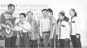  ??  ?? FAZZRUDIN (kiri) menyampaik­an bantuan alat tulis kepada sebahagian daripada 113 murid tahun enam SJK Chung Hua, Batu 7, Jalan Matang yang bakal menduduki UPSR tahun ini.