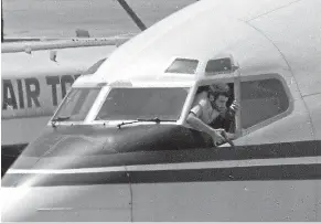  ?? AP ?? A hijacker points a weapon at a media crew from the cockpit of a TWA jet at Beirut Internatio­nal Airport, Lebanon, on June 19, 1985, during a hijacking.