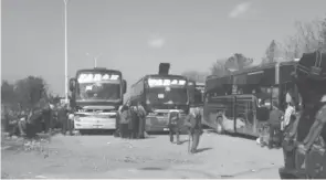  ??  ?? Un combattant rebelle devant des bus transporta­nt des personnes évacuées la veille de localités syriennes loyalistes, hier, à Rachidine, une banlieue rebelle à l’ouest d’Alep