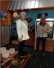  ?? JORDANA JOY — THE MORNING JOURNAL ?? Elane Mattmuller, 60, of Vermilion, left, stands in a Tibetan singing bowl as a part of Christina Grozik’s, right, demonstrat­ion.