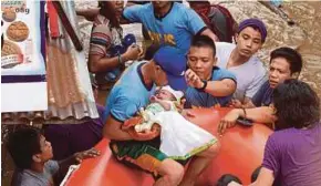  ?? AFP PIC ?? Policemen evacuating a baby in Cagayan de Oro, Mindanao, yesterday, after the Cagayan River swelled due to heavy rains brought by Tropical Storm Tembin.