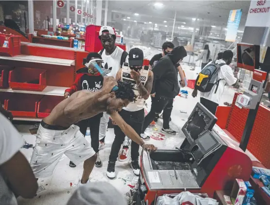  ?? Picture: AP ?? MAYHEM: A looter targets a cash register at a Target store in Minneapoli­s as rioting engulfed the city of St Paul for a second night.